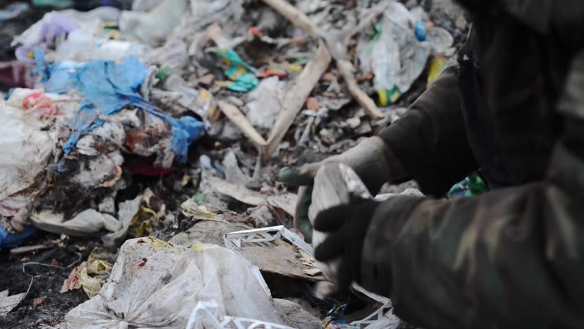 Poor dirty homeless is searching for food in pile of garbage at junkyard, illustration of inequality in capitalism society  Royalty-Free Stock Footage #1011145472
