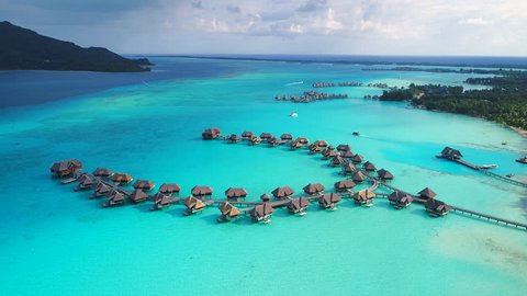 Aerial view of tropical paradise of Bora Bora, turquoise crystal clear water of scenic lagoon, typical overwater bungalows - South Pacific Ocean, French Polynesia, 4k UHD