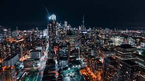 Downtown Toronto skyline at night with bright city lights from office buildings and condos. Cars travelling creating light trails that depict a fast paced developing city. Perfect for tourism videos, 
