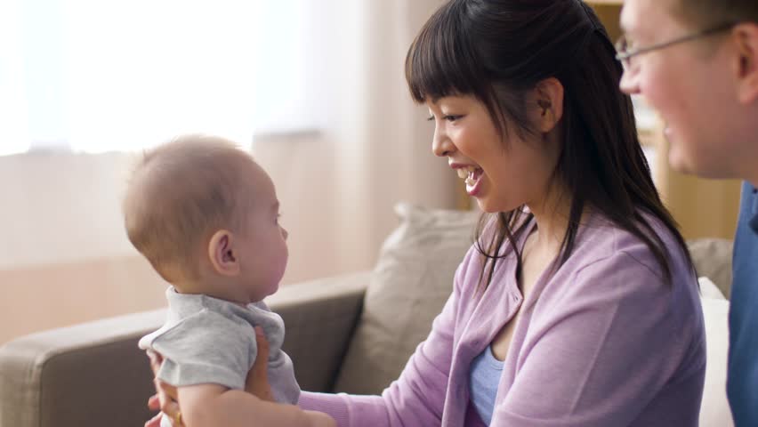 Family, parenthood and people concept - happy mother and father with baby boy at home | Shutterstock HD Video #1011150596