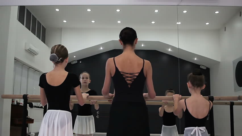 small ballerinas do port de bras together with proffesional teacher. Back view