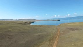 Aerial view of dirt road to the blue water coast on sunny day, Olkhon, Baikal lake