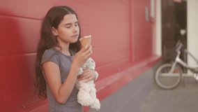 little girl eating ice cream the street with a soft toy motion slow motion video. girl and ice cream lifestyle eat concept