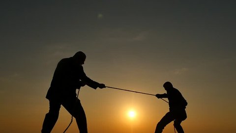 competition concept - tug of war - 2 persons pulls rope silhouettes
