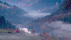 4k time lapse video of fog moving in a rural gorge mountain area with forest and houses in the background.