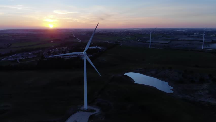 Aerial view of windmills at sunset, Renewable energy from turbines rotating with the sun behind Royalty-Free Stock Footage #1011181064