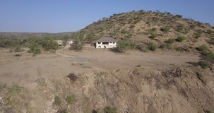4K aerial summer video of African savanna, abandoned dilapidated house surrounded by bush hills in Daan Viljoen National Reserve in Khomas Hochland area near Windhoek, Namibia's capital, Africa