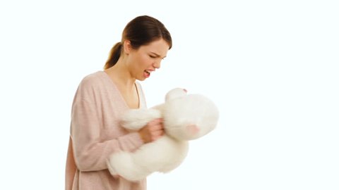 Angry girl is screaming at teddy bear, isolated