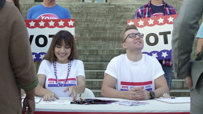 A young man and a woman dispensing flags at a political rally