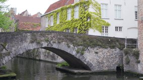 Out of focus background plate of canal in Bruges with Bridge crossing river. Blurry video backdrop of brick bridge in old European town for compositing. 4k