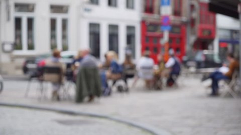 Out of focus background plate of European cafe patio street scene for compositing. Defocused video backdrop of people sitting outside coffee shop for green screen. 4k