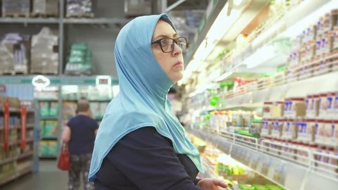 woman in hijab 40 years shopping, chooses baby food