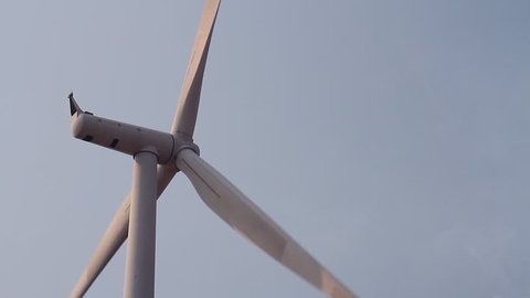 Close up of wind turbine electric power generator on blue sky