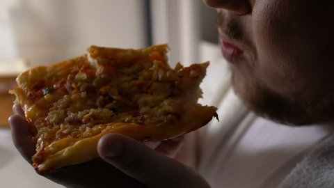 Lazy fat bachelor chewing pizza near fridge at night, cheap food nutrition
