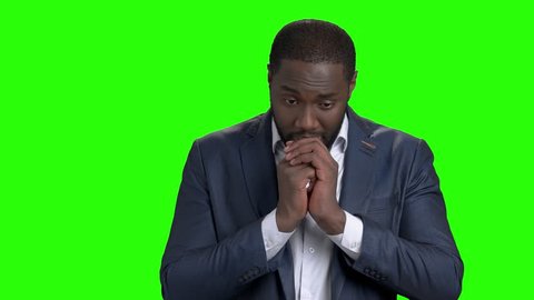 Portrait of businessman regretting about something. Unhappy afro american entrepreneur with clasped hands on chroma key background.