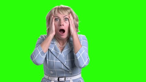 Horrified mature woman on green screen. Caucasian middle-aged woman looking frightened and shocked on chroma key background. Human negative expressions.