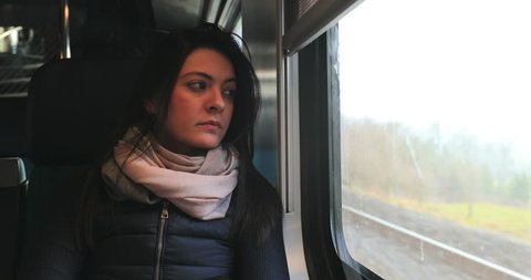 Woman looking out train window looking at landscape passing by