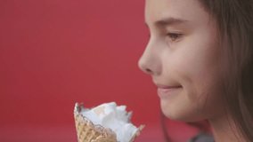 Pretty baby girl kid eating slow motion video nursing bottle licking big ice cream in waffle cone with raspberry happy laughing on red background. lifestyle the girl teenager and ice cream concept