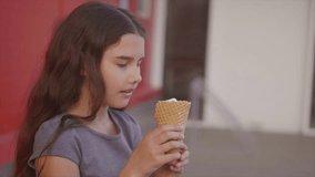 Pretty baby girl kid eating slow motion video nursing bottle licking big ice cream in waffle cone with raspberry happy laughing on red background. the girl teenager and ice lifestyle cream concept