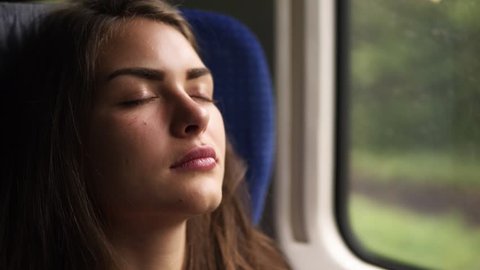 Woman tourist traveling by train. Local train. Young female relaxing sleeping in modern train. Slight natural shaking. Close up