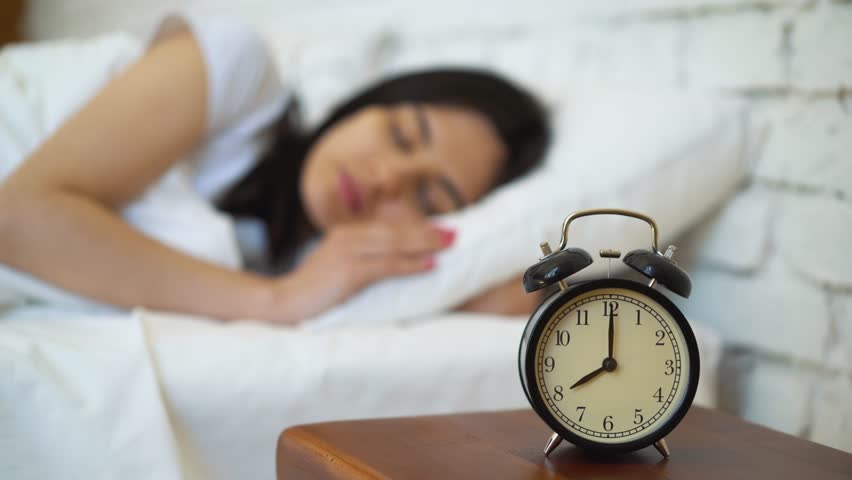 Tired brunette turning off her alarm clock in her bedroom. Royalty-Free Stock Footage #1011239915