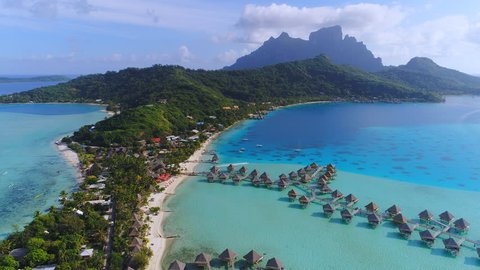Aerial view of tropical paradise of Bora Bora island, turquoise crystal clear water of scenic blue lagoon, typical over water bungalows, Matira Point - South Pacific Ocean, French Polynesia from above