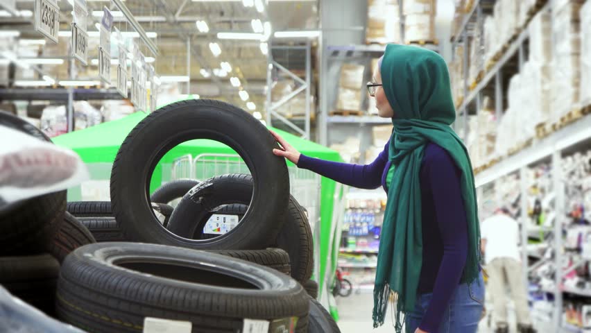 attractive Muslim girl shopping, choose automobile tire