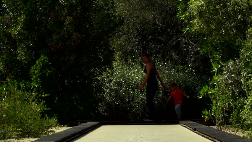 Funny little boy with mom runs and jumps on the trampoline track in the Park.