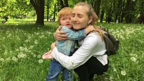Happy mother hugs her little daughter  in green field of grass in nature. Happy family concept. Outdoors. Portrait, face. video 4k.