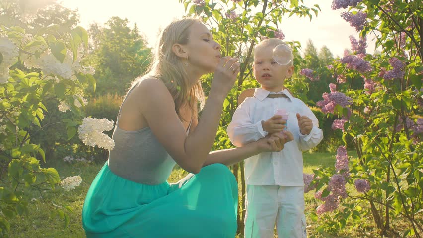A happy mother is playing with children in a park outside.