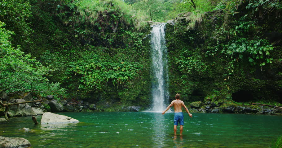 Young man discovers amazing waterfall, travel and adventure lifestyle