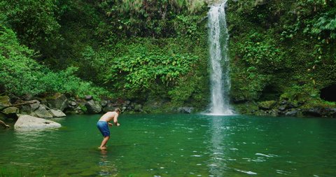 Young man dives into beautiful tropical waterfall, travel and adventure lifestyle