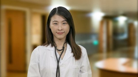 Asian female doctor showing thumbs up gesture in hospital
