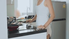 Funny video of young woman doing exercise in kitchen while cooking scones on pan. Housewife doing pushups and turning homemade indian chapati on a pan. Healthy lifestyle concept.