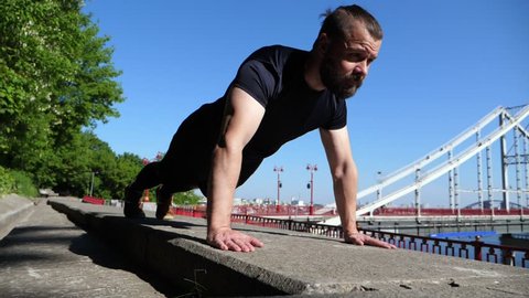 The Bearded Man Is Working Out In Outdoor Urban Environment. Push Ups.