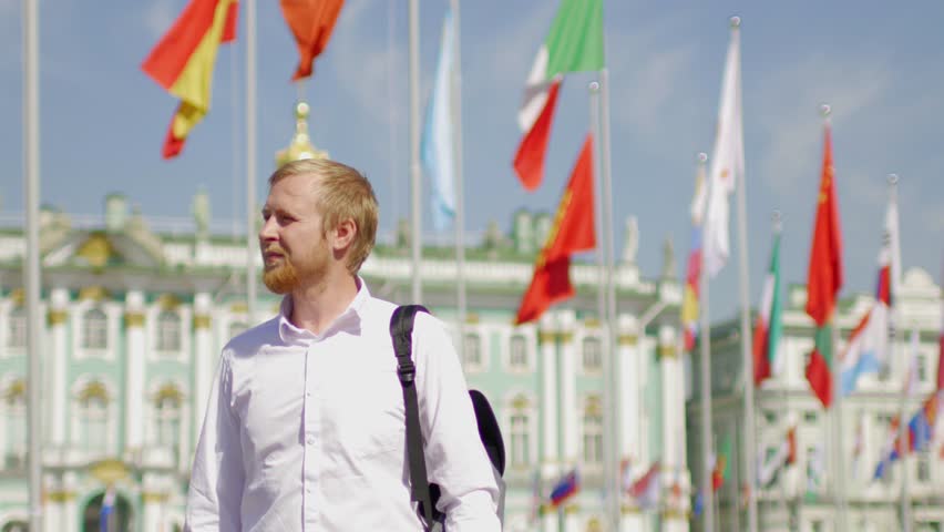 man in a white shirt against the background of the flags of the world