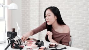 Young beautiful Asian woman professional beauty vlogger or blogger recording make up tutorial to share on social media, slow motion