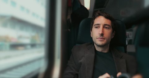 Passenger putting headphones on whil traveling by train and looking out window on commute
