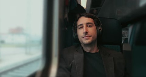 Passenger removing headphones and looking out window while riding train