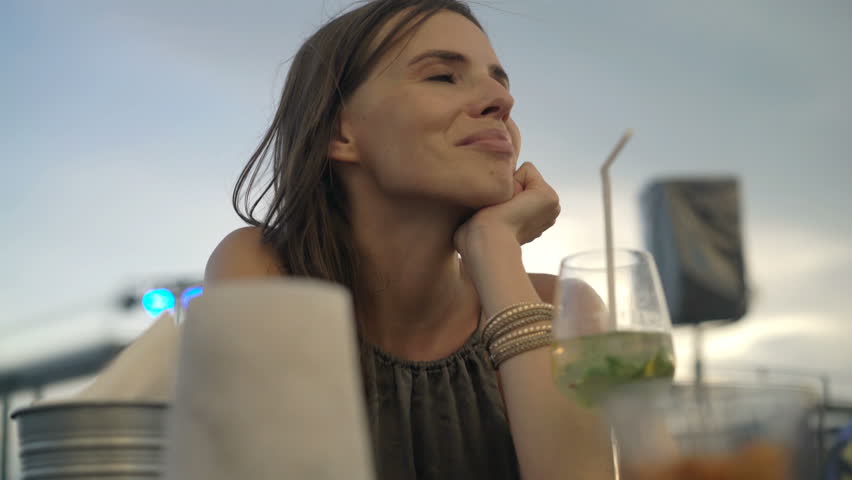 Happy, young woman drinking cocktail sitting in cafe
