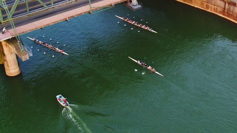 Drone Aerial view of sweep Rowing boats passing under the bridge while traffic and cyclists and runners pass over it