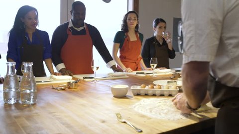 Chef teaching his students how to knead dough