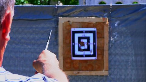 The man throws a knife into the target from a distance, the knife does not hit the target. Throwing knives at the target from an open-air distance, flying knives, sharp knives fly in a target from the