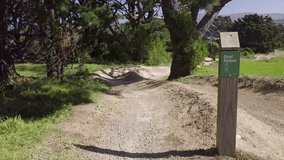 Aerial, flying down mountain / dirt bike path on hill.