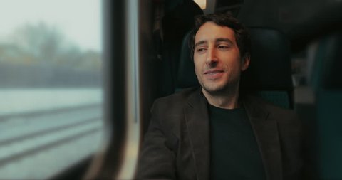 Happy fullfilled man riding train and looking out window