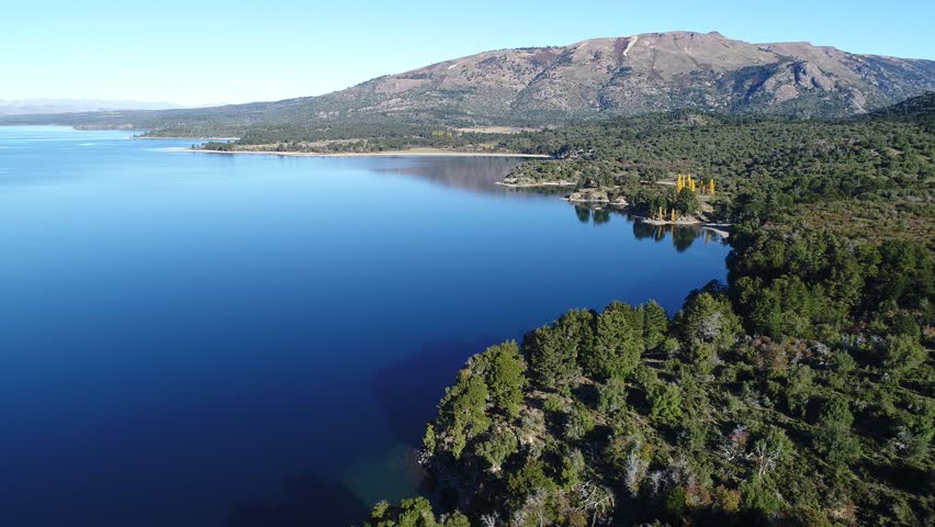 Aerial drone scene of Alumine lake. Camera travels fowards with a high point of view of bays, beaches, rocky and coasts. Mountains on the background. Turistic area five lagoons. Mapuche area.