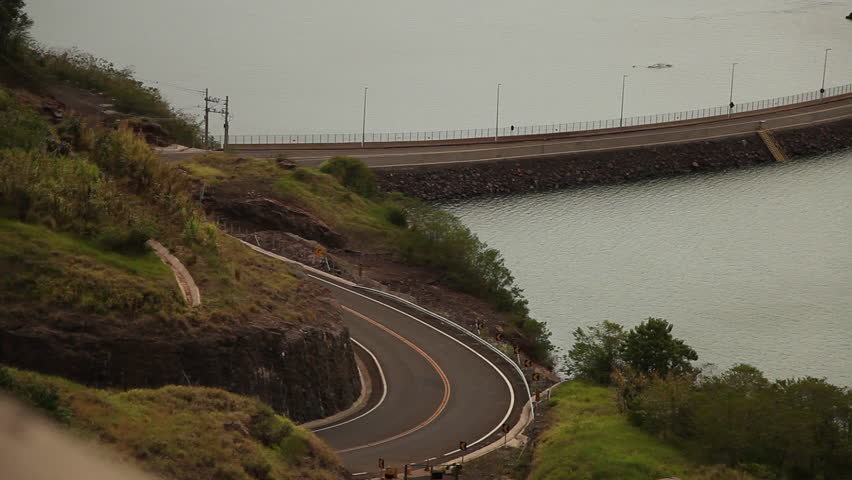 Car on the winding wind of a dam.
