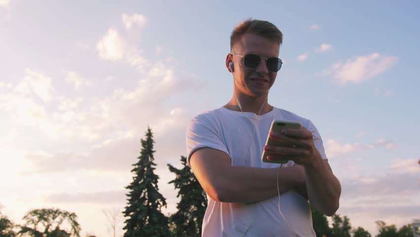 Handsome young hipster man using smartphone outdoors in park