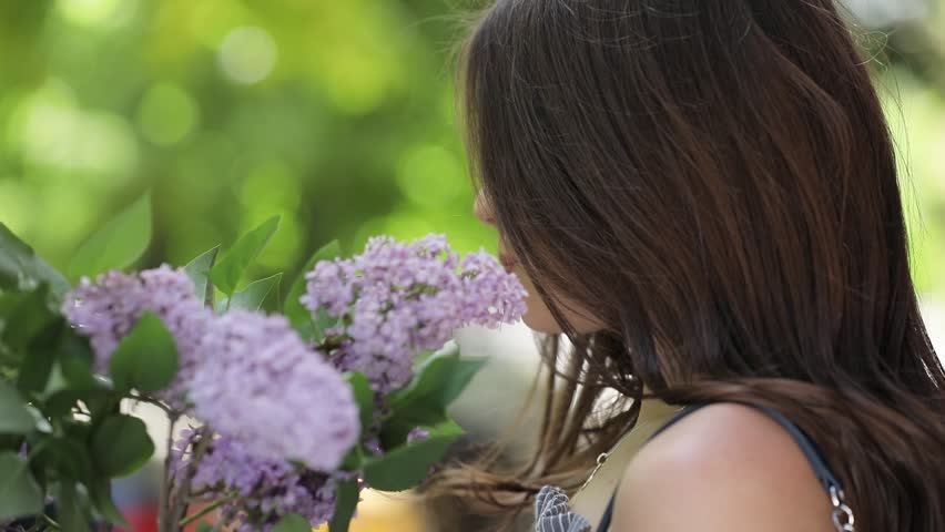 Happy young woman smiling keeping lilac flowers