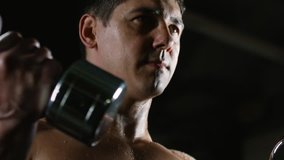 Tilt down of muscular shirtless bodybuilder with sweaty torso doing dumbbell curls - Powered by Shutterstock - Get 15% off with code: PIKWIZARD15